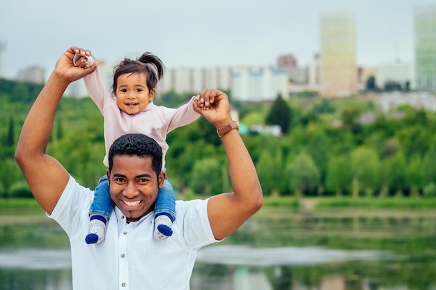 Afro-Vater umarmt ihre gemischtrassige Tochter und verbringt Zeit im Garten.