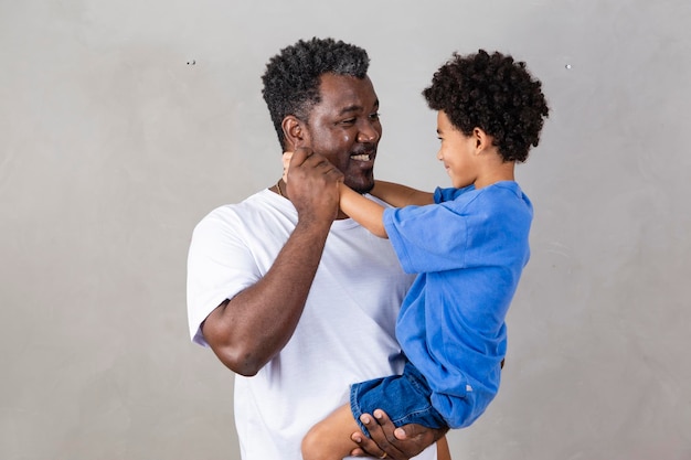 Afro-Vater und schwarzer Sohn auf grauem Hintergrund lächelnd und glücklicher Afro-Vati am Vatertag Vatertag im August