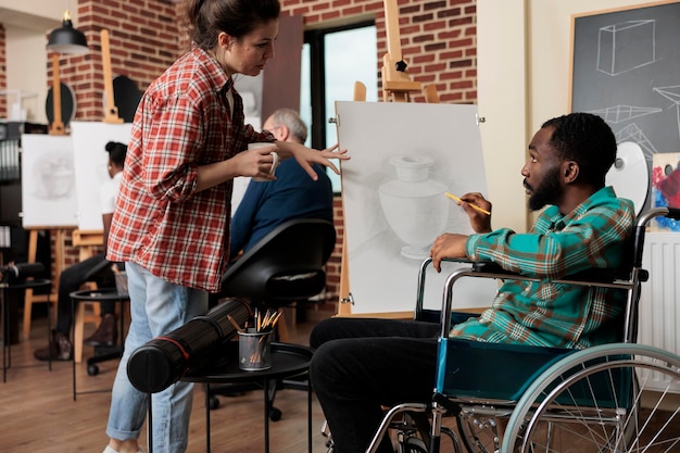 Foto un afroamericano discapacitado hablando con un maestro durante una clase de dibujo grupal, mejorando las habilidades sociales a través de obras de arte colaborativas. enseñar arte a personas con discapacidad.
