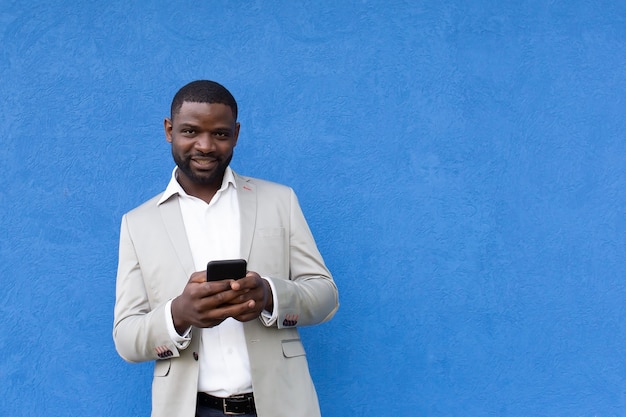 El afroamericano feliz con teléfono sobre fondo azul.