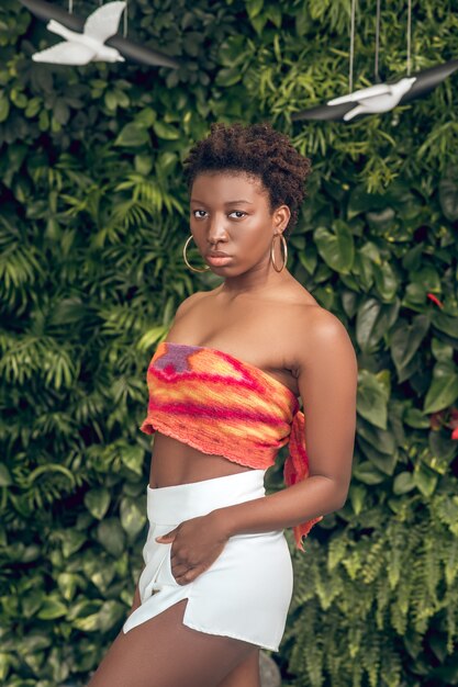 Afroamericano. Mujer joven de piel oscura en un top brillante y pantalones cortos blancos