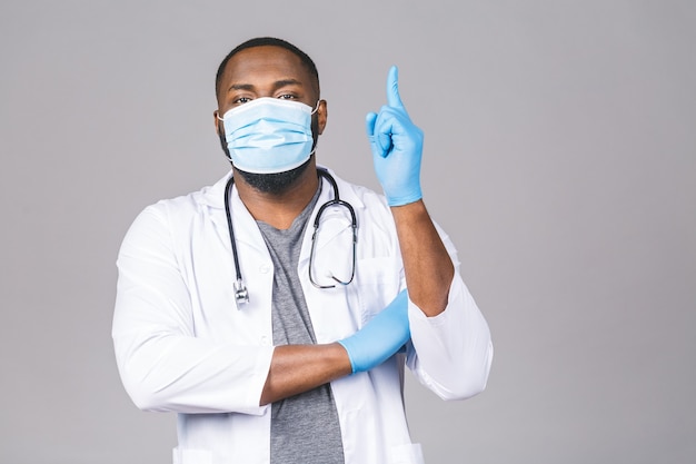 Afroamerikaner Arzt Mann im medizinischen Kleid sterile Maske Handschuhe. Zeigender Finger.