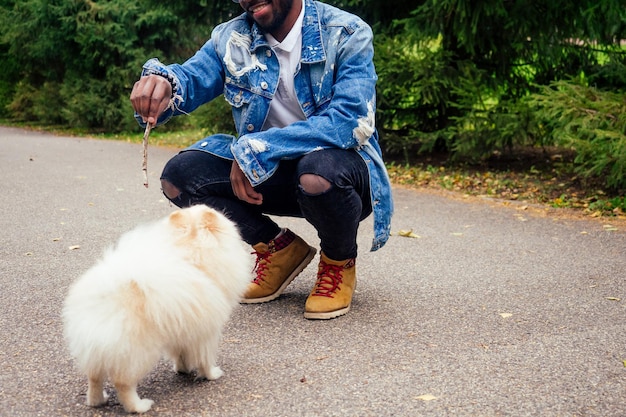 Afroamerikaner, der mit seinen flauschigen Spitzhundeteams auf der Straße spazieren geht