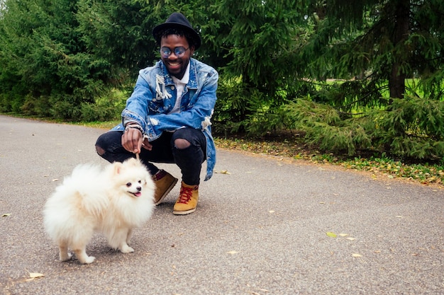 Afroamerikaner, der mit seinen flauschigen Spitzhundeteams auf der Straße spazieren geht