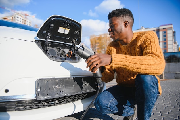 Afroamerikaner, der sein Elektroauto auflädt.