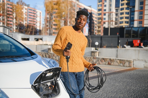 Afroamerikaner, der sein Elektroauto auflädt.