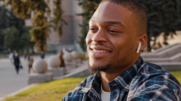 Afroamerikaner, gutaussehender junger Mann, der Musik über drahtlose Kopfhörer im Stadtzentrum hört