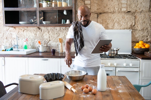 Afroamerikaner kocht, während er sich das Rezept online auf seinem Tablet ansieht