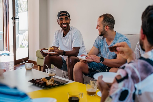 Afroamerikaner lächelt, während er Gebäck bei einem Treffen von Freunden isst