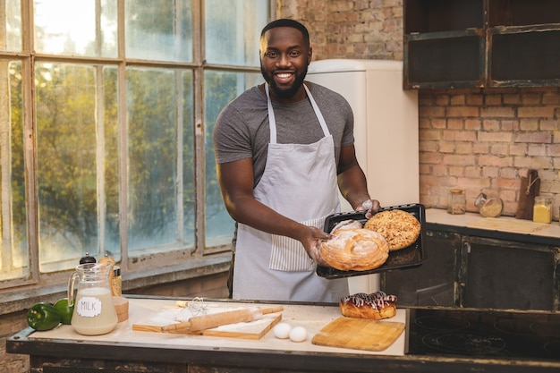 Afroamerikaner Mann, der Schürze und Backen trägt