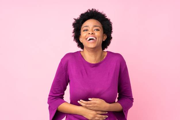 Afroamerikanerfrau auf isoliertem rosa viel lächelnd