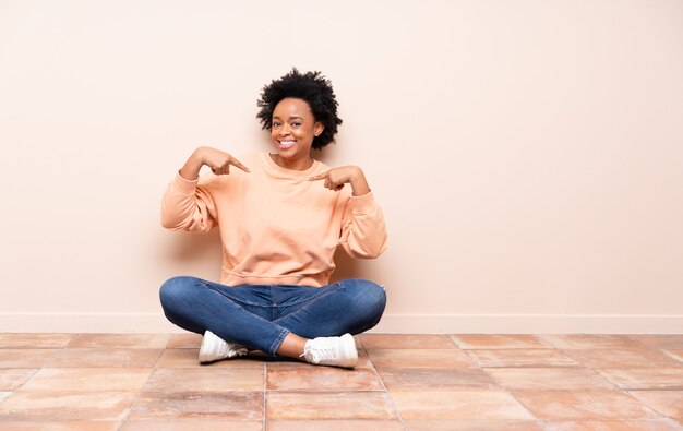 Afroamerikanerfrau, die auf dem Boden sitzt