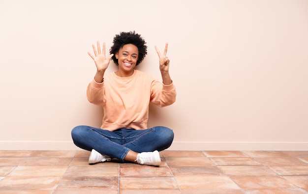 Afroamerikanerfrau, die auf dem Boden sitzt