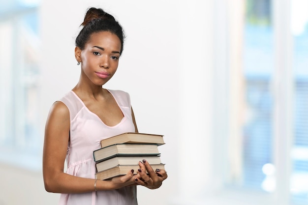 Afroamerikanerfrau, die einen Stapel Bücher hält