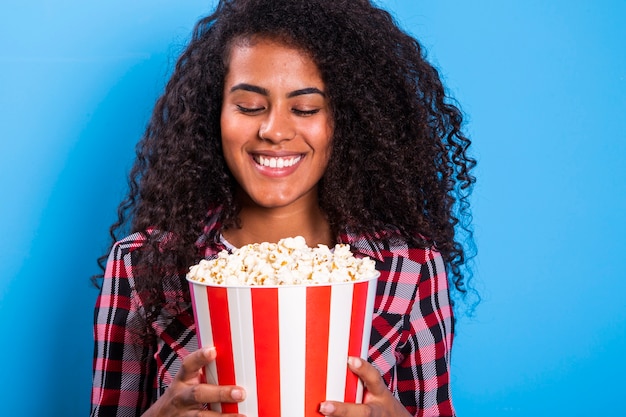 Afroamerikanerfrau, die Popcorn glücklich mit großem Lächeln isst