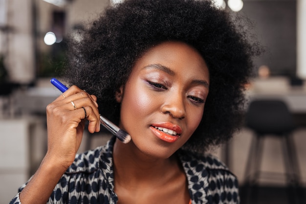 Afroamerikanerfrau mit dem lockigen Haar, das während der Videoaufnahme positiv aussieht