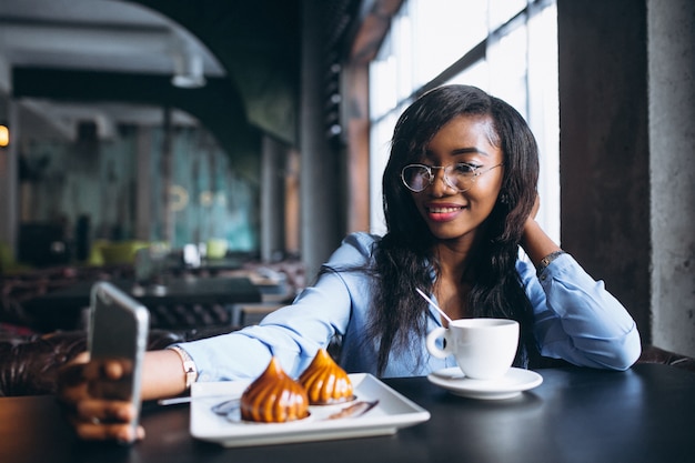 Afroamerikanerfrau mit Telefon in einem Café