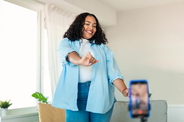 Afroamerikanerfrau tanzt und macht zu Hause ein Video am Telefon