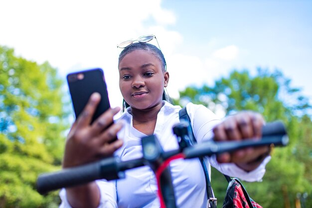 Afroamerikanerin aktiviert und bezahlt einen gemieteten Escooer oder ein E-Bike auf der Straße