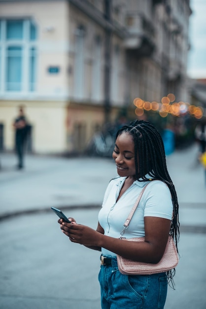Afroamerikanerin benutzt Smartphone, während sie in der Stadt ist
