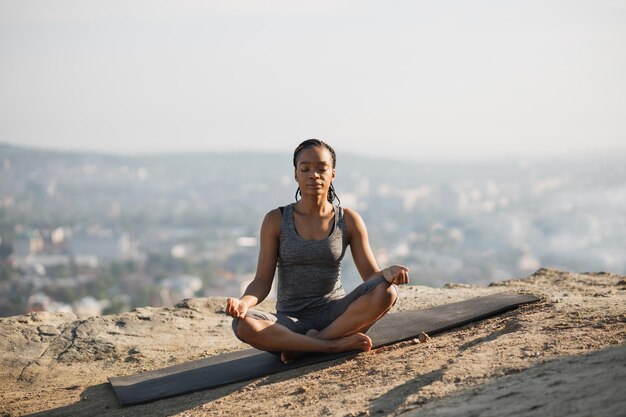 Afroamerikanerin, die draußen auf einer Yogamatte meditiert