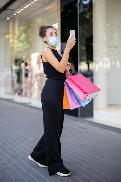 Afroamerikanerin, die eine Virenschutzmaske mit bunten Paketen trägt a