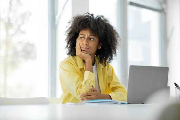 Afroamerikanerin, die schlechte Nachrichten erhält, ist traurig bei der Arbeit im Innenbereich.