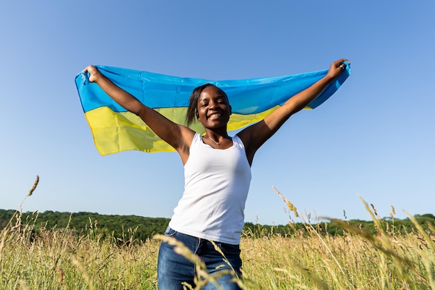 Afroamerikanerin, eingewickelt in die ukrainische gelb-blaue Flagge, nationales Symbol der Ukraine