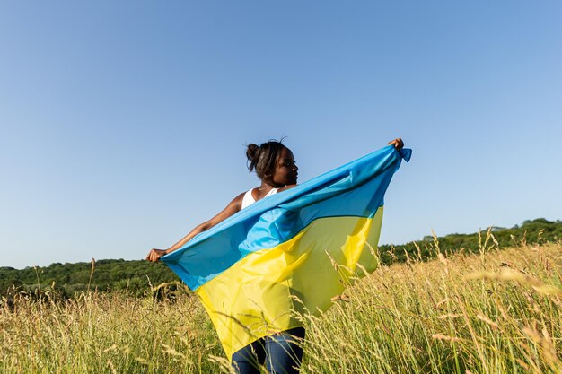 Afroamerikanerin, eingewickelt in die ukrainische gelb-blaue Flagge, nationales Symbol der Ukraine