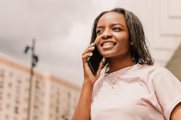Afroamerikanerin hält Handtelefon, surft im Internet und chattet mit Freunden und Kollegen
