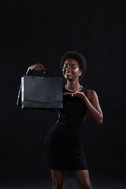 Afroamerikanerin hält schwarze Einkaufstaschen Verkauf und Rabatte auf Markt und Black Friday Konzept