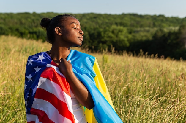 Afroamerikanerin in amerikanische und ukrainische Flagge gehüllt