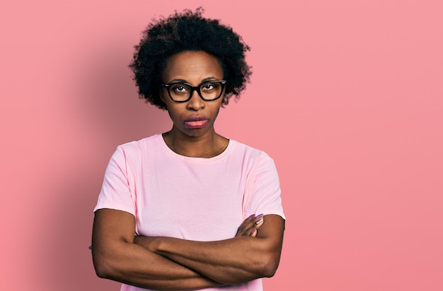 Afroamerikanerin mit afro-haar trägt lässige kleidung und brille skeptisch und nervös missbilligender ausdruck im gesicht mit verschränkten armen negative person