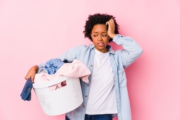 Afroamerikanerin mittleren Alters, die Wäsche macht, die schockiert ist, sie hat sich an wichtiges Treffen erinnert.
