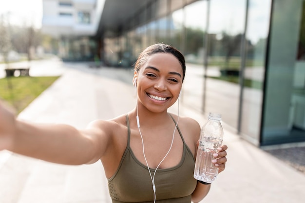 Afroamerikanerin nimmt Selfie mit Handy auf und nimmt Video für ihren Blog auf, der Wasser hält