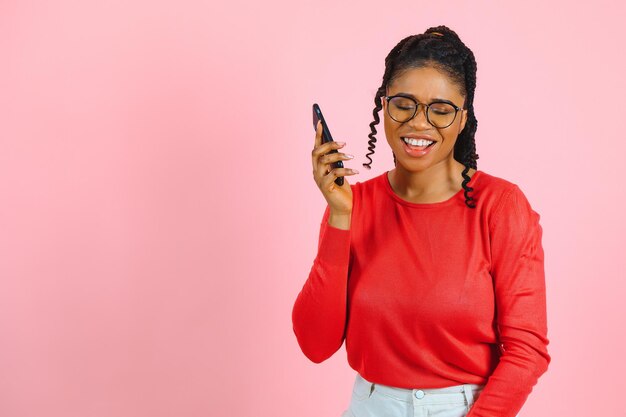 Afroamerikanerin über isoliertem rosa Hintergrund, die eine Nachricht mit dem Handy sendet