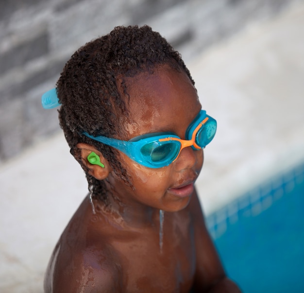 Afroamerikanerkind mit Schutzbrillen im Pool