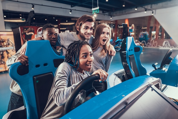 Afroamerikanermädchen, das blaues Auto in Arkade reitet.