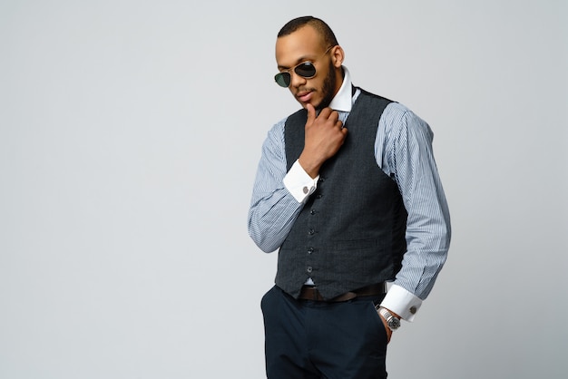 Afroamerikanermann, der Hemd und Krawatte über graue Wand trägt