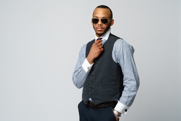 Afroamerikanermann, der Hemd und Krawatte über graue Wand trägt