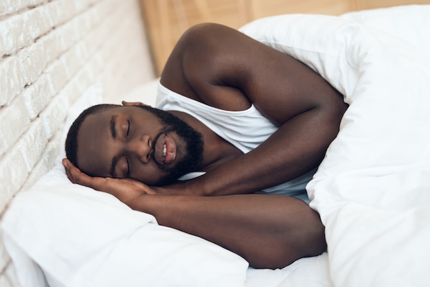 Afroamerikanermann, der im Bett schläft.