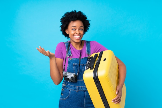 Afroamerikanerreisendfrau mit Koffer über blauer Wand