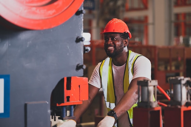Afroamerikanische Arbeiter, die am Tag der Fabrikarbeit schwere Maschinen kontrollieren