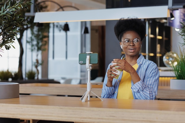 Afroamerikanische Bloggerin in einem Coworking kommuniziert per Videochat oder schaut sich ein Training an