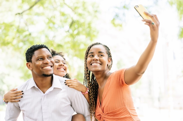 Afroamerikanische Familie, die Spaß hat und einen Tag im Park genießt, während sie ein Selfie zusammen mit einem Handy macht.