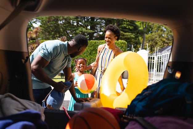 Afroamerikanische Familie verstaut ihr gesamtes Gepäck hinten im Auto