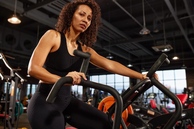 Afroamerikanische Frau Cardio zur Gewichtsreduktion, Aerobic-Training auf dem Fahrrad, aktiver Lebensstil, gemeinsame Gesundheit, regelmäßiges Training