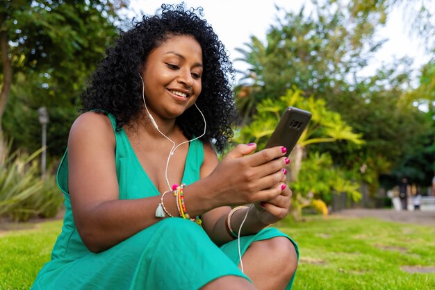 Afroamerikanische Frau, die Musik im Park hört