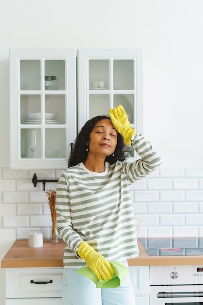 Foto afroamerikanische frau fühlt sich erleichtert, nachdem sie die küche gereinigt hat und von den hausaufgaben müde ist