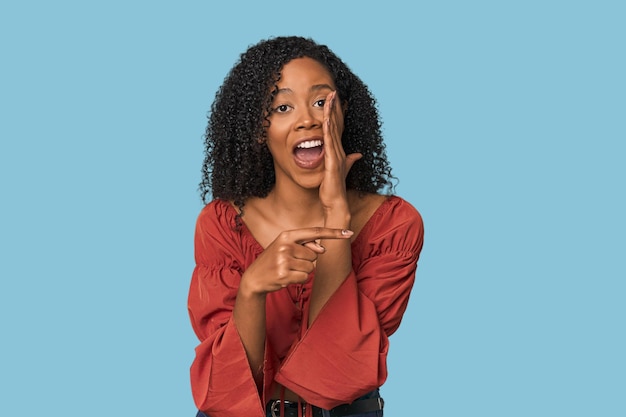 Foto afroamerikanische frau in einem studio, die ein gerücht erzählt, auf die seite zeigt und etwas berichtet